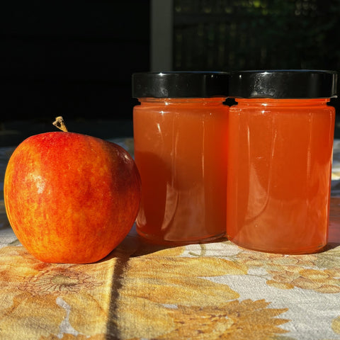 Two jars of apple jelly and an apple