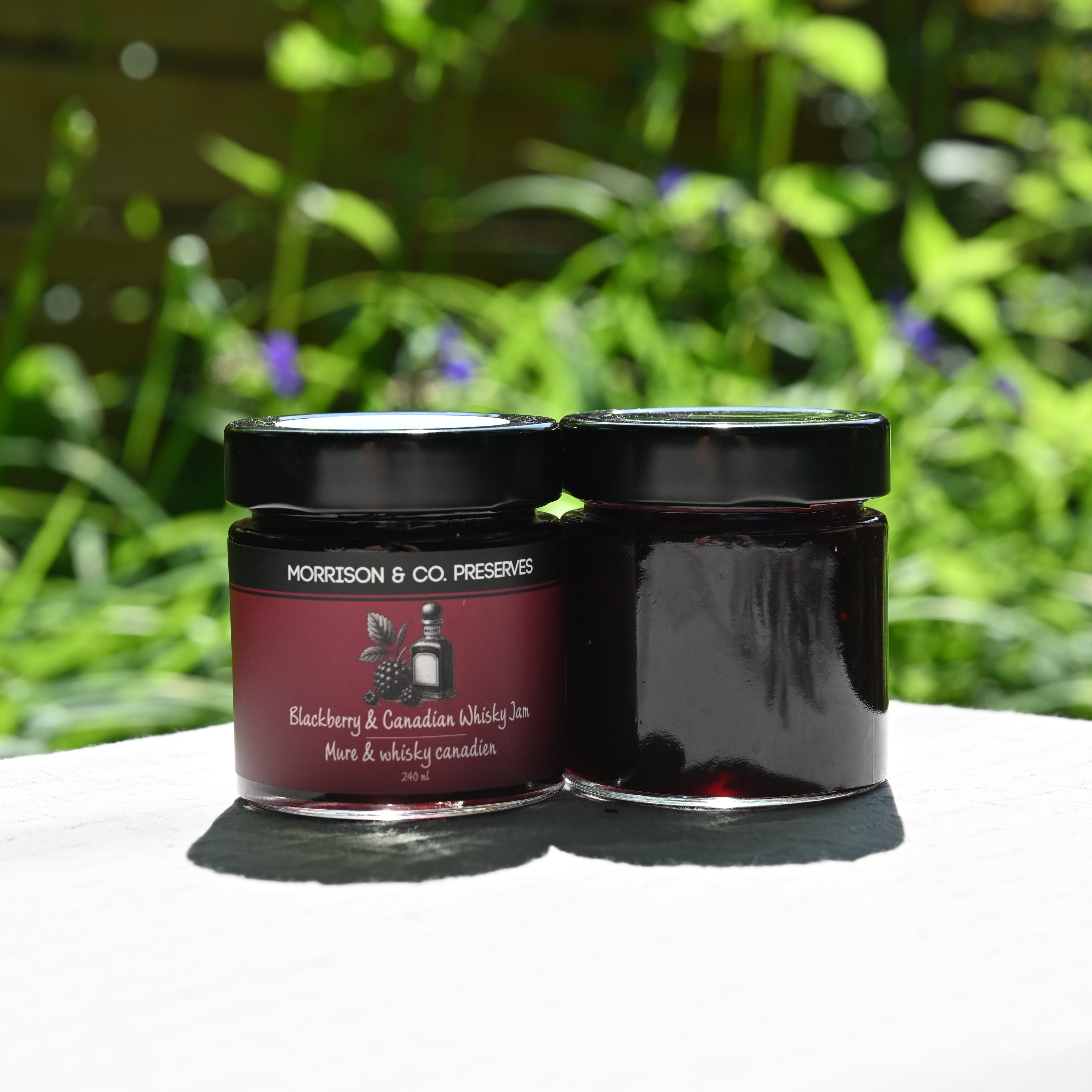 Two jars of Morrison & Co. preserves with a blurred green outdoor background