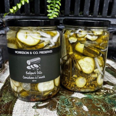 Two jars of dill pickled cucumbers with a label on a decorative surface