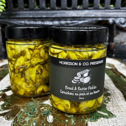 Two jars of bread and butter pickles with a label on a decorative surface