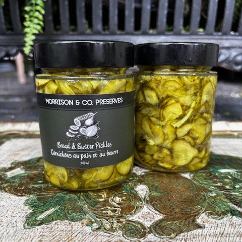 Two jars of Morrison & Co. Preserves Bread & Butter Pickles on a decorative surface.