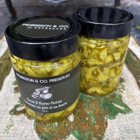 Two jars of Morrison & Co. Preserves bread and butter pickles on a textured surface.