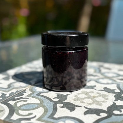 Jar oof Morrison & Co Blueberry Jam without a label n a patterned surface with a blurred background
