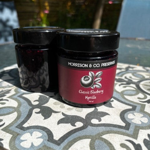 Two jars of Morrison & Co. Blueberry Preserves on a patterned table