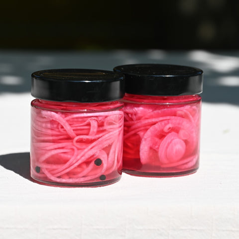 Two jars of pickled red onion and peppercorns