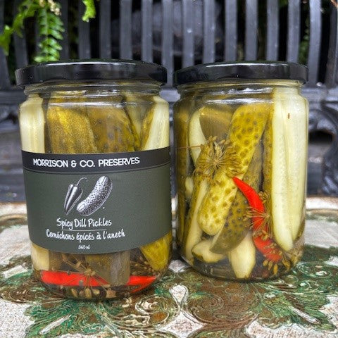 Two jars of spicy dill pickles with a label on a decorative surface