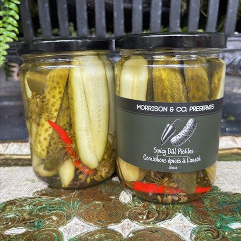 Two jars of Morrison & Co preserves spicy dill pickles with a label on a decorative surface